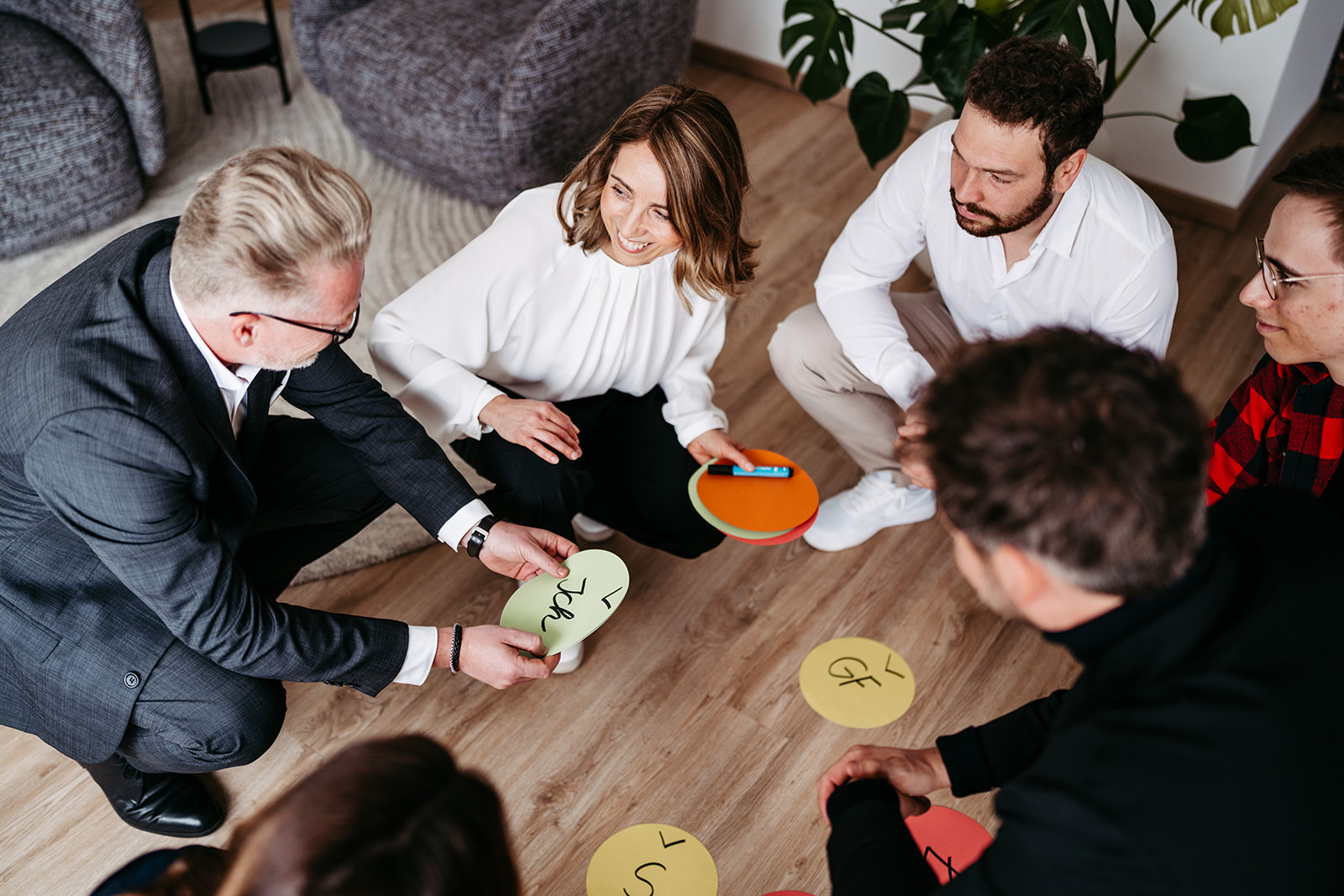 Menschen bei Gruppenarbeit am Boden mit Wortkarten